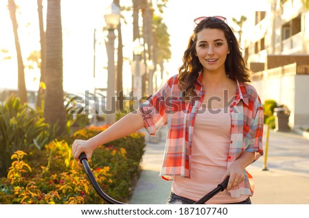 Young woman posing with bike - Smiling young woman holding bike handlebars with sunglasses on her head