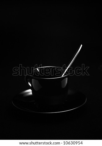 Black cup with high-grade steel spoon in front of black background