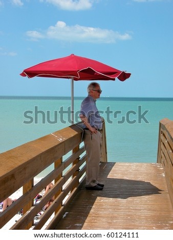 Man at pier under red umbrella in Naples, Florida