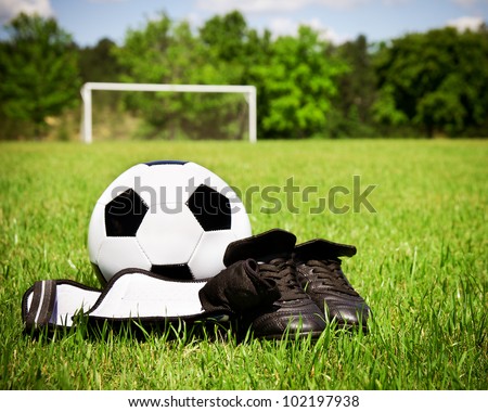 Child sports concept with soccer ball, cleats, shin guards on field