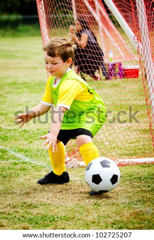 Young child boy playing soccer goalie during organized league game