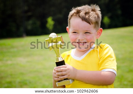 Young soccer player in uniform with his new trophy