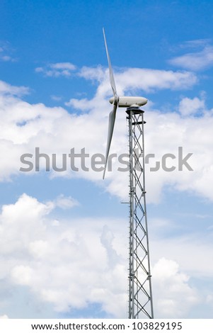 Side view of industrial wind turbine under cloudy blue sky