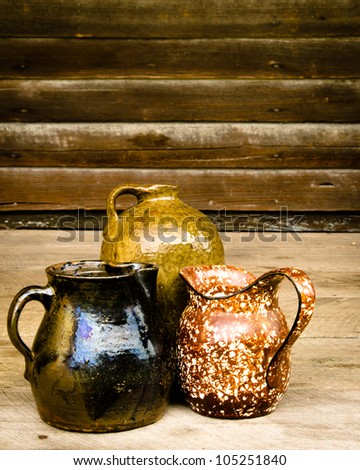 Collection of vintage antique Depression-era clay containers under window on porch of old cabin