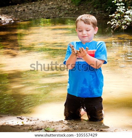 Child playing in mud in forest creek