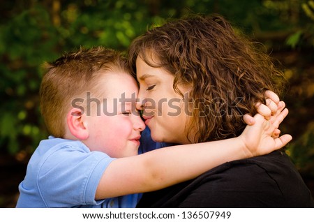 Mother and son hugging with woman kissing child