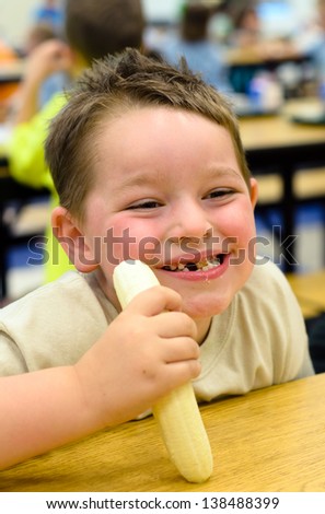 Happy child eating healthy lunch in busy school cafeteria