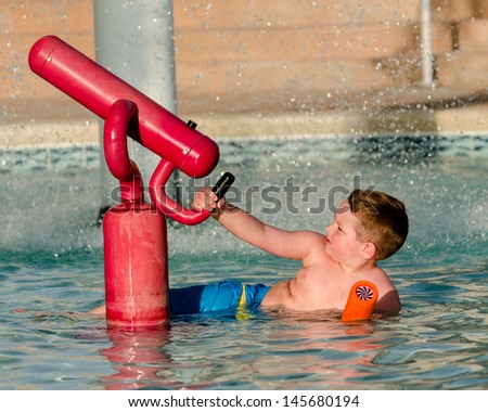 Child playing with water cannon at kiddie pool during summer