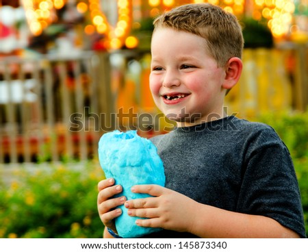 Happy child eating cotton candy at carnival