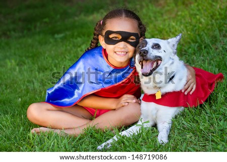 Pretty Mixed Race Girl Hugging Her Pet With Both Dressed Up In Super Hero Costumes
