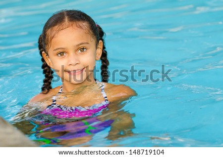 Portrait of happy pretty mixed race child by side of pool during summer