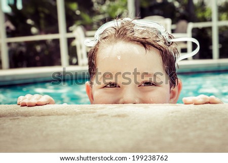 Young child peeking out of pool while swimming in vintage filtered image