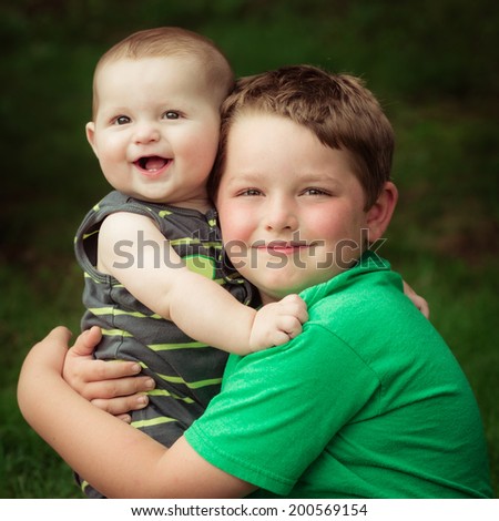 Happy brothers hugging in summer portrait outdoors in vintage filtered image
