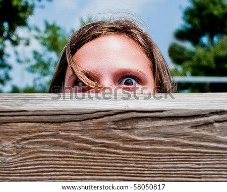 Girl peeks over log at playground.