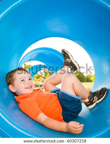 Cute young child boy or kid playing in tunnel on playground.