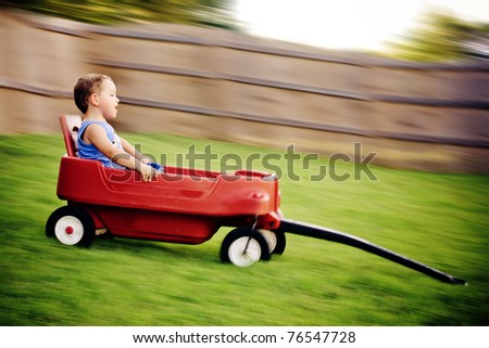 Young boy zooms downhill in wagon in image with motion blur.