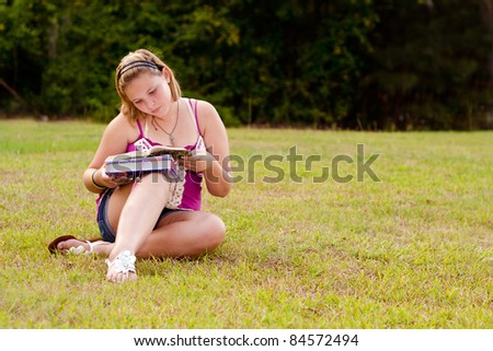 Teenage girl studying for school outdoors on field