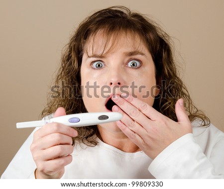 Shocked, stunned and surprised middle-aged woman holding a positive pregnancy test