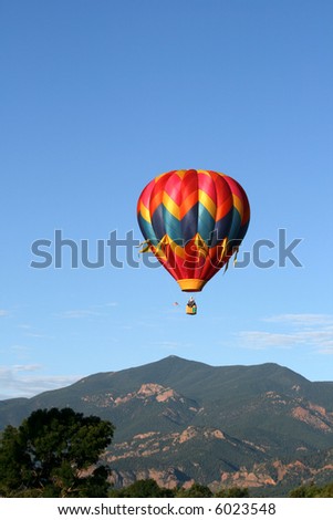 Single hot air balloon with the Rocky Mountains as backdrop
