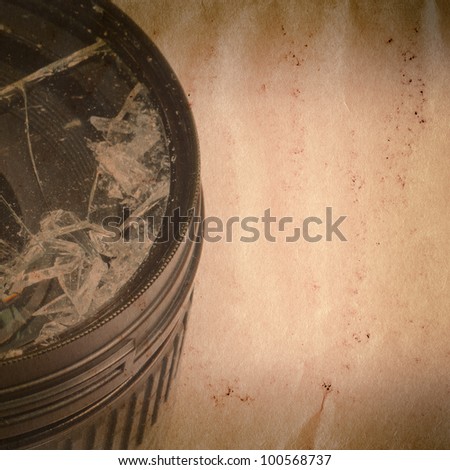 Broken DSLR camera lens on old grunge paper texture background