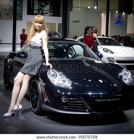 GUANGZHOU, CHINA - NOV 26: unidentified model with Porsche Cayman Black Edition sport car at the 9th China international automobile exhibition. on November 26, 2011 in Guangzhou China.