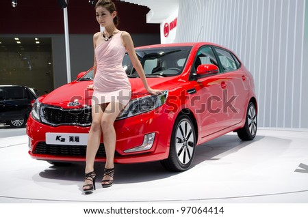 GUANGZHOU, CHINA - NOV 26: unidentified model with KIA K2 car at the 9th China international automobile exhibition. on November 26, 2011 in Guangzhou China.