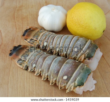 Delicious lobster tails with lemon and garlic on a wooden cutting board perfect for summer grilling!