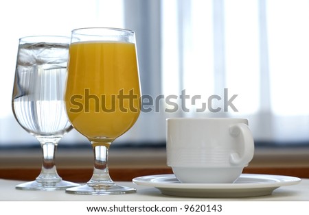 Morning beverage service featuring orange juice, coffee and ice water.  The morning sun streams in through the window.