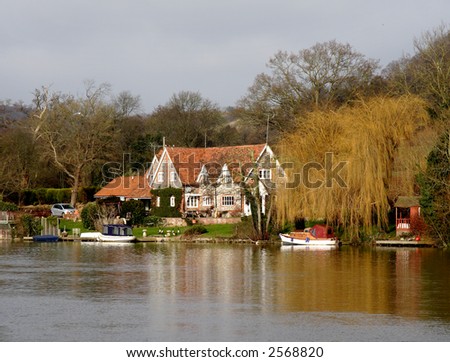 Winter scene of a Brick and Flint House  on the banks of a River in England