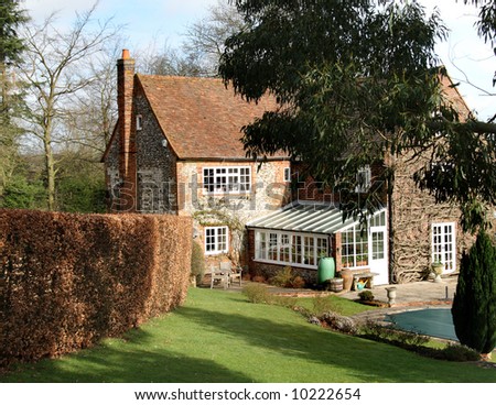 Traditional Brick and Flint English Rural House and garden with Beech hedge