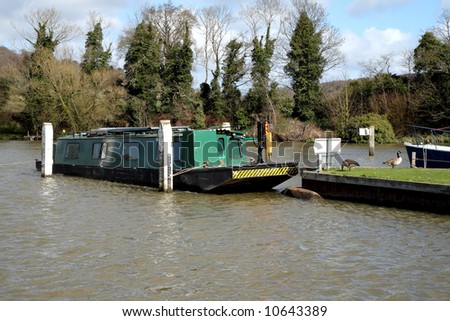 Narrow-boat moored on a Choppy River Thames with Canada Geese sitting on the bank