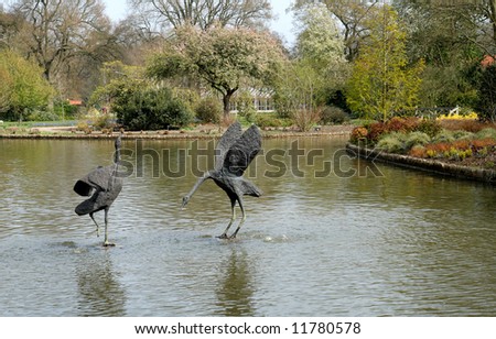 Bird Sculpture in an English Garden Lake with trees and flower beds along the Bank