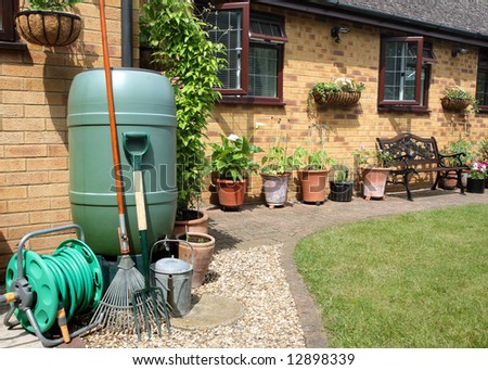 An English back garden with Water Butt, flowerpots, garden tools and Hose Pipe
