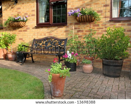 English garden Patio area with Bench seat and planters with flowers and Plant and Vegetables growing.