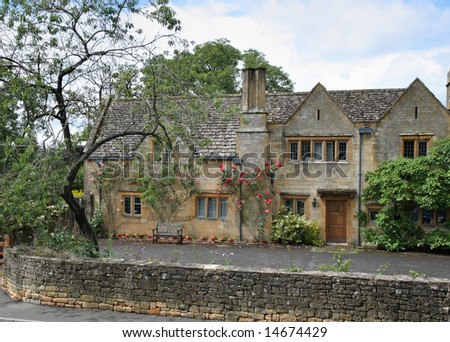 Traditional Stone Medieval English Village House and garden with climbing Roses on the wall