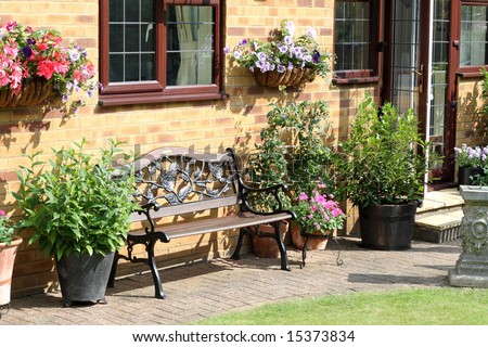 An English Back garden with bench seat, flower filled wall baskets and flowerpots