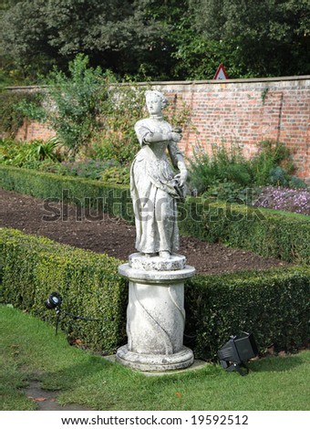Statue of a Lady in an English garden with Box Hedging and wall behind