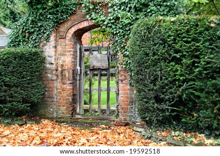 Rustic red brick Arched Gateway with fallen Autumn leaves on the ground
