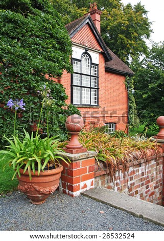 Traditional Red Brick English Country House and garden with flowerpot on the terrace