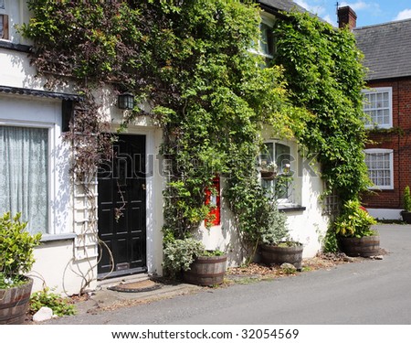 Traditional whitewashed English Village Cottage with climbing plants on the Wall and Postbox