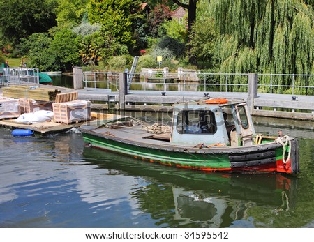 Boat towing a Pontoon of building supplies along the River Thames in England