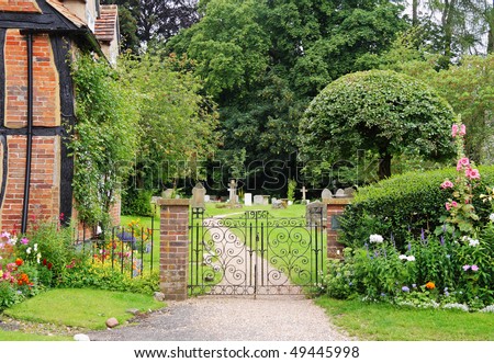 Wrought Iron Gate to an English Churchyard and Cemetery with cottage and flower filled garden