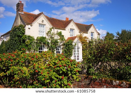 English Rural House and garden with ripening rose-hips growing along the wall