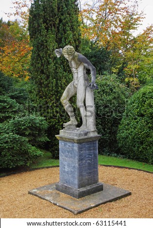 Stone Statue of a Discus thrower on a Plinth with autumn colors behind