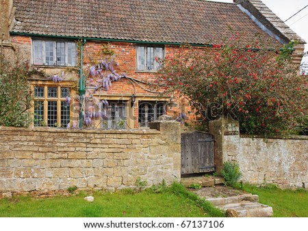 Traditional English Village Cottage and garden with Climbing Wisteria on the Wall and stone wall