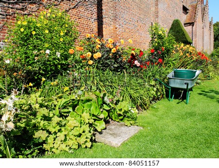 Wheelbarrow parked next to a colorful border of Summer Flowers in an English walled garden