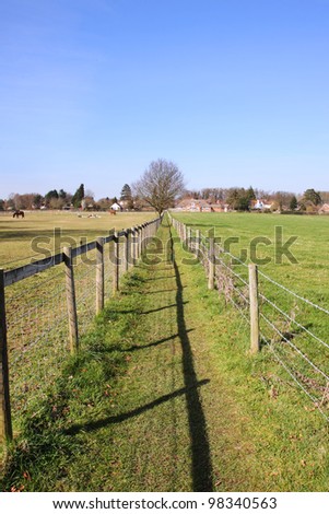 Footpath between two fields in rural England with barbed wire fence