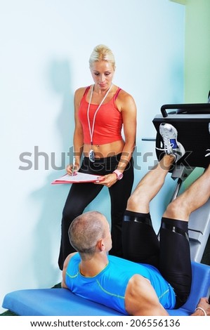 Athlete man in gym with personal fitness trainer
