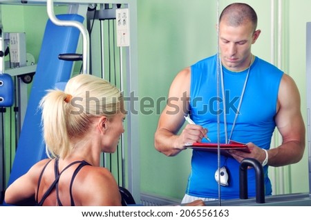 Woman in gym exercising with personal fitness trainer