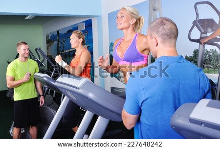 Two women in gym exercising with personal fitness trainer